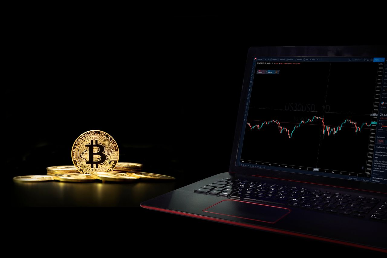 services-02 Golden bitcoin coins next to a laptop displaying a trading graph, symbolizing digital currency investment.